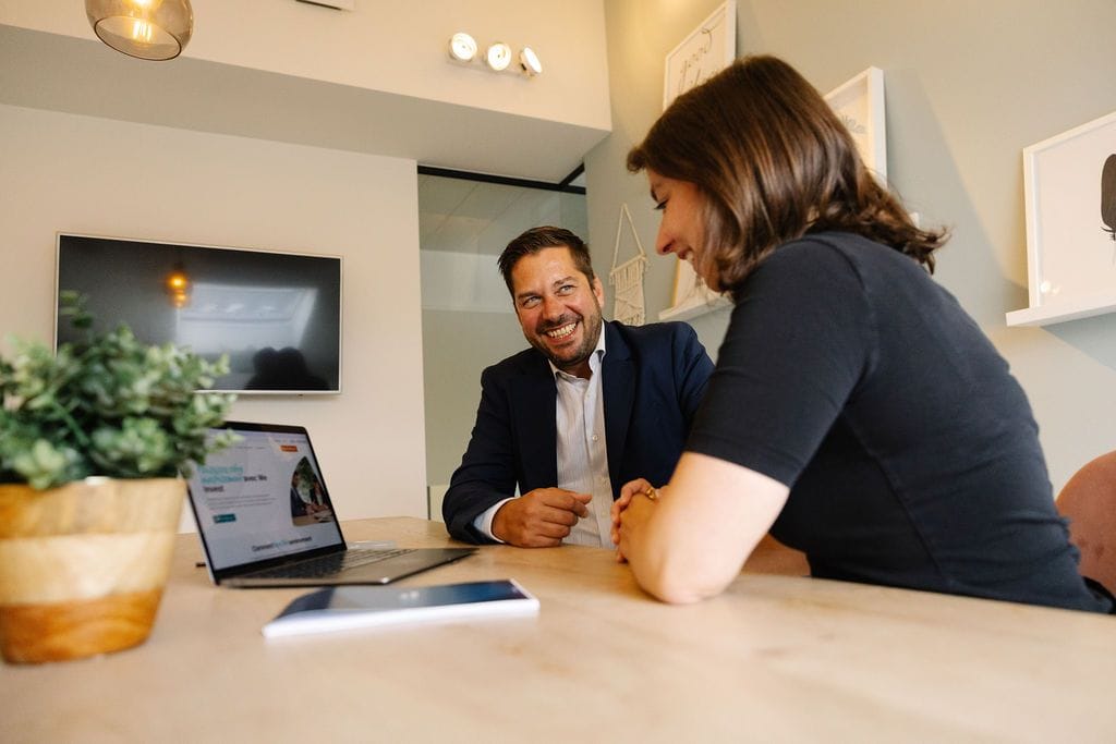 Une propriétaire échange avec son conseiller référent We Invest autour d’un ordinateur portable
