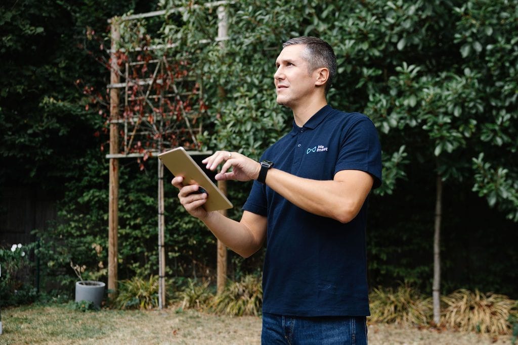 Un conseiller We Invest réalise l’état des lieux d’un bien sur tablette, dans le jardin