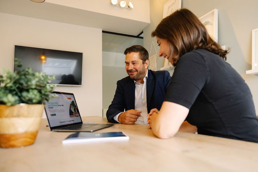 Un conseiller We Invest et une cliente en rendez-vous, le site We Invest ouvert sur un ordinateur portable