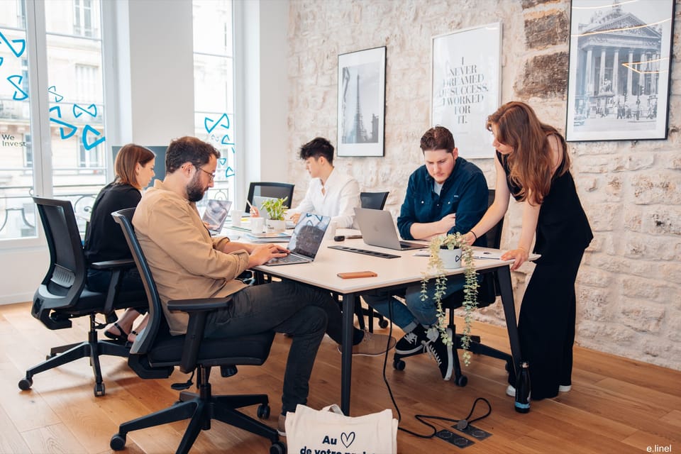 L’équipe We Invest réunie autour d’une table de travail